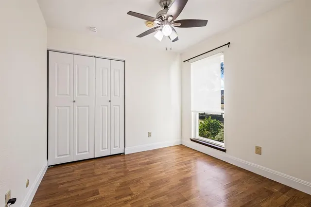 an empty room with wooden floor fan and windows