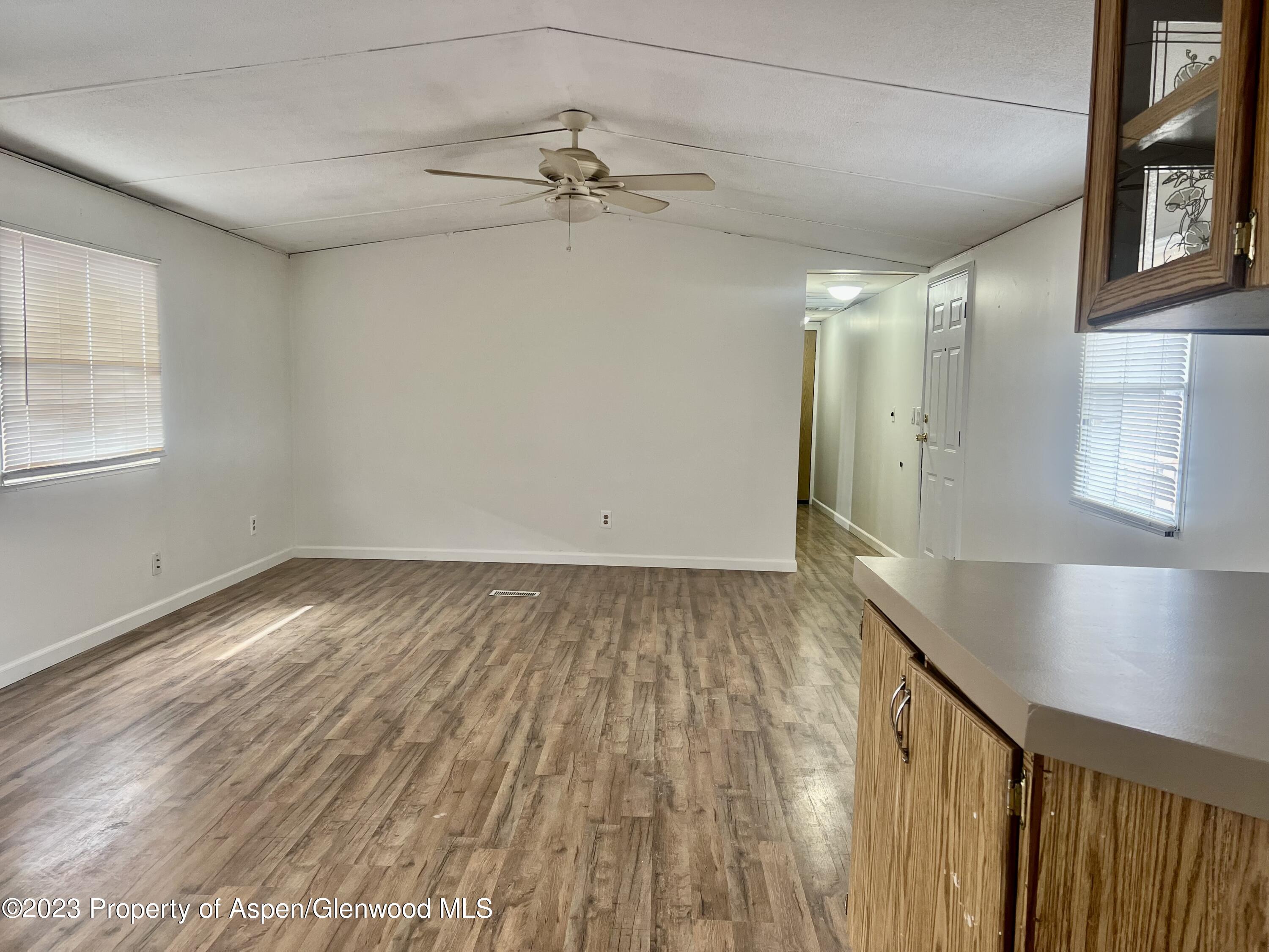 346 Greig Avenue De Beque, CO 81630 - Photo 6 of 15 an empty room with wooden floor fan and windows