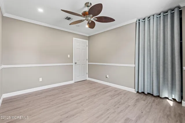 an empty room with wooden floor closet fan and windows
