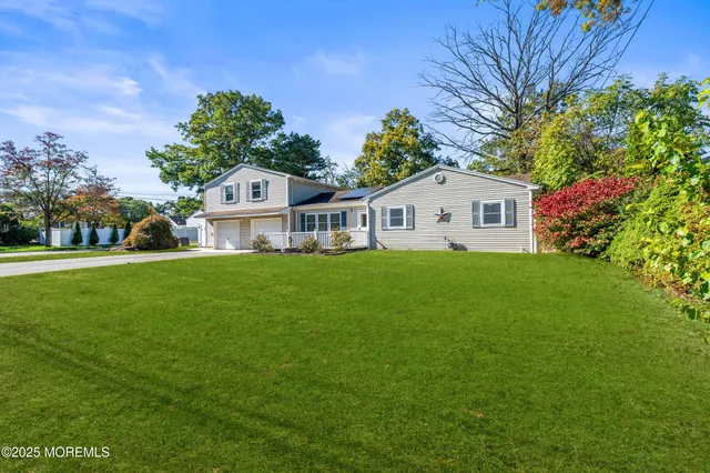 a front view of a house with garden and trees
