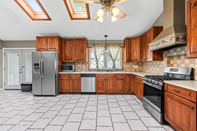 a kitchen with stainless steel appliances granite countertop a refrigerator a sink dishwasher a stove with wooden cabinets and floor