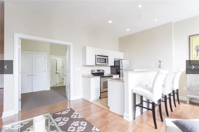 a living room with stainless steel appliances kitchen island granite countertop a refrigerator and a sink