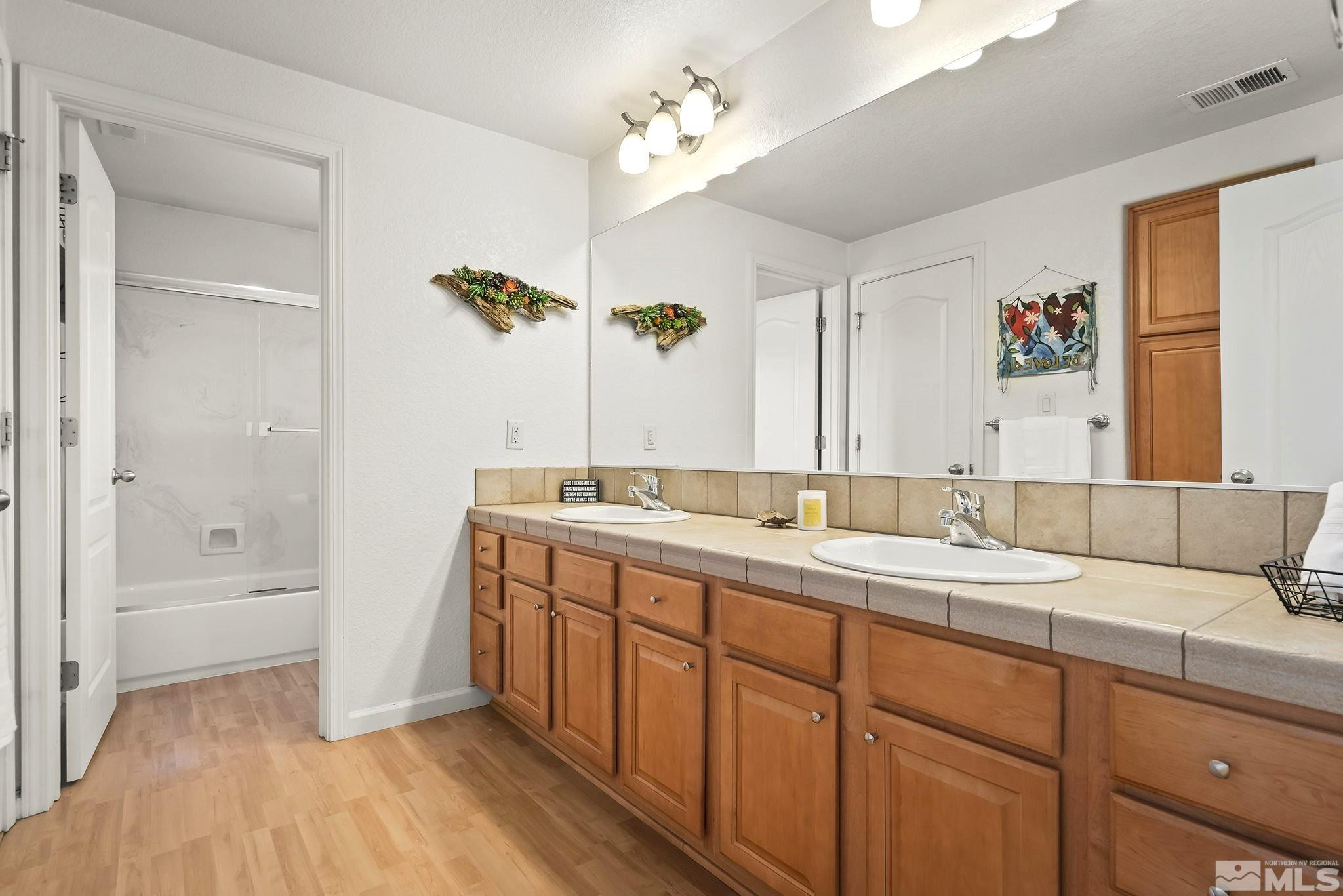10031 Cascade Falls Drive Reno, NV 89521 - Photo 19 of 30 a bathroom with a double vanity sink a mirror and a bathtub