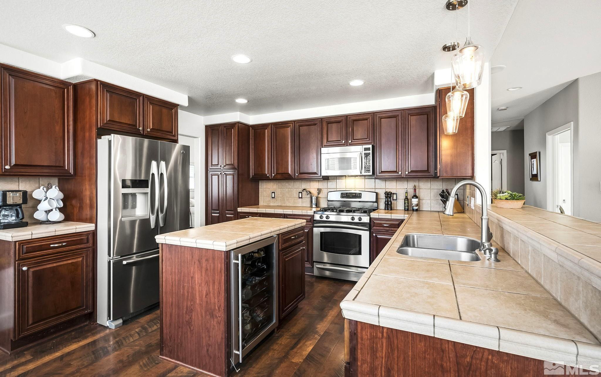 10031 Cascade Falls Drive Reno, NV 89521 - Photo 4 of 30 a kitchen with stainless steel appliances granite countertop a stove top oven a refrigerator a sink and dishwasher