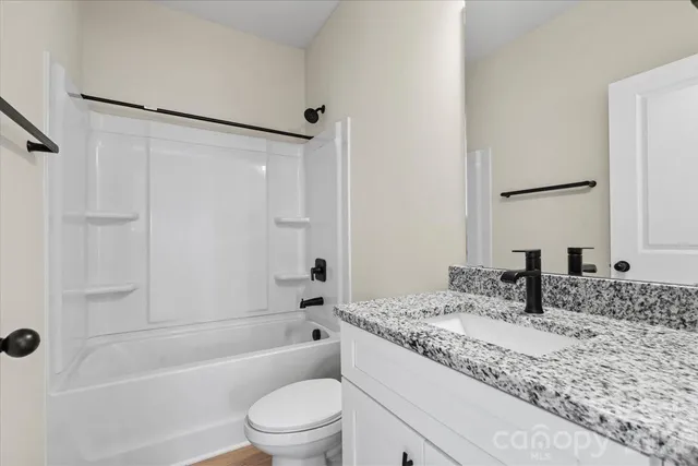 a bathroom with a granite countertop toilet a sink and a bathtub