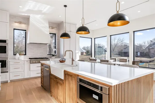 a kitchen with stainless steel appliances a stove a sink a center island a stove and a wooden floor