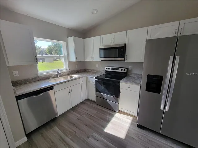 a kitchen with a sink a refrigerator a window and cabinets
