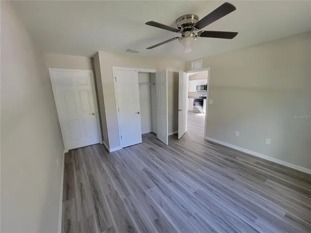 an empty room with wooden floor and a ceiling fan