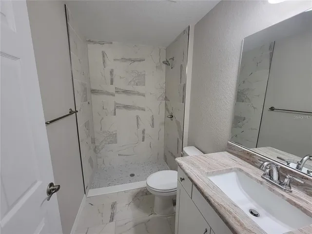 a bathroom with a granite countertop sink toilet and shower