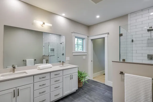 a spacious bathroom with double vanity a mirror and a shower