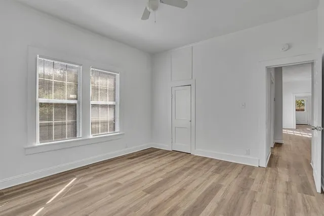 an empty room with wooden floor and windows