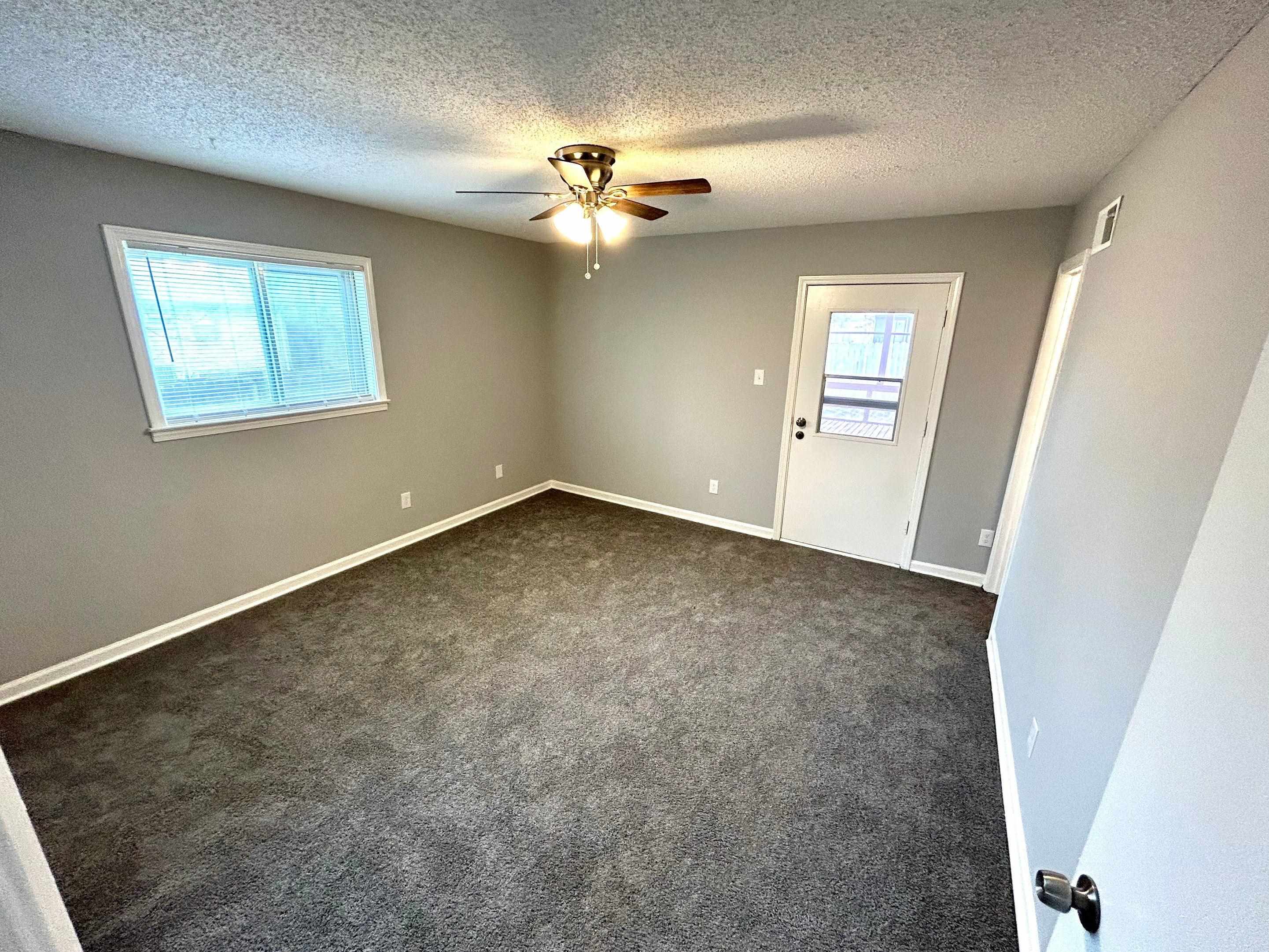 Empty room featuring dark carpet, a ceiling fan, and a textured ceiling
