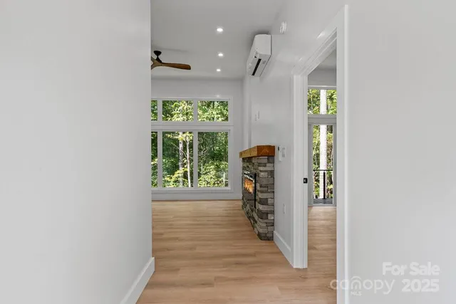 a view of an empty room with wooden floor and a window