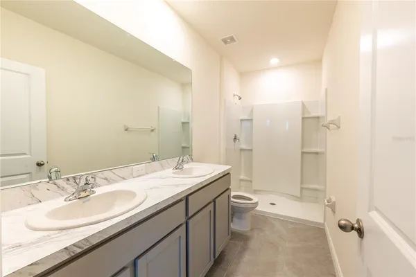 a bathroom with a double vanity sink toilet mirror and shower