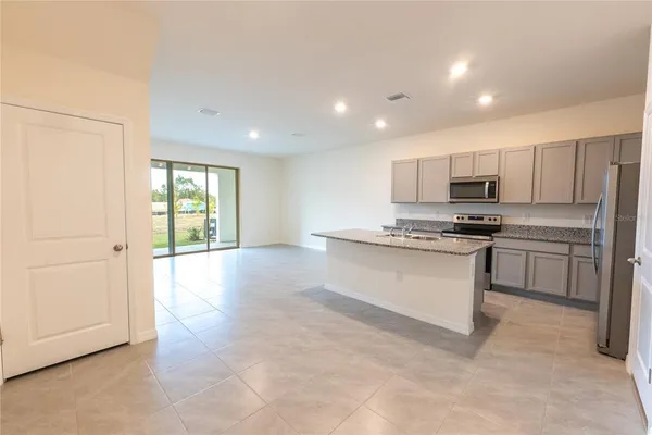 a kitchen with stainless steel appliances granite countertop a stove a sink and a refrigerator with white cabinets