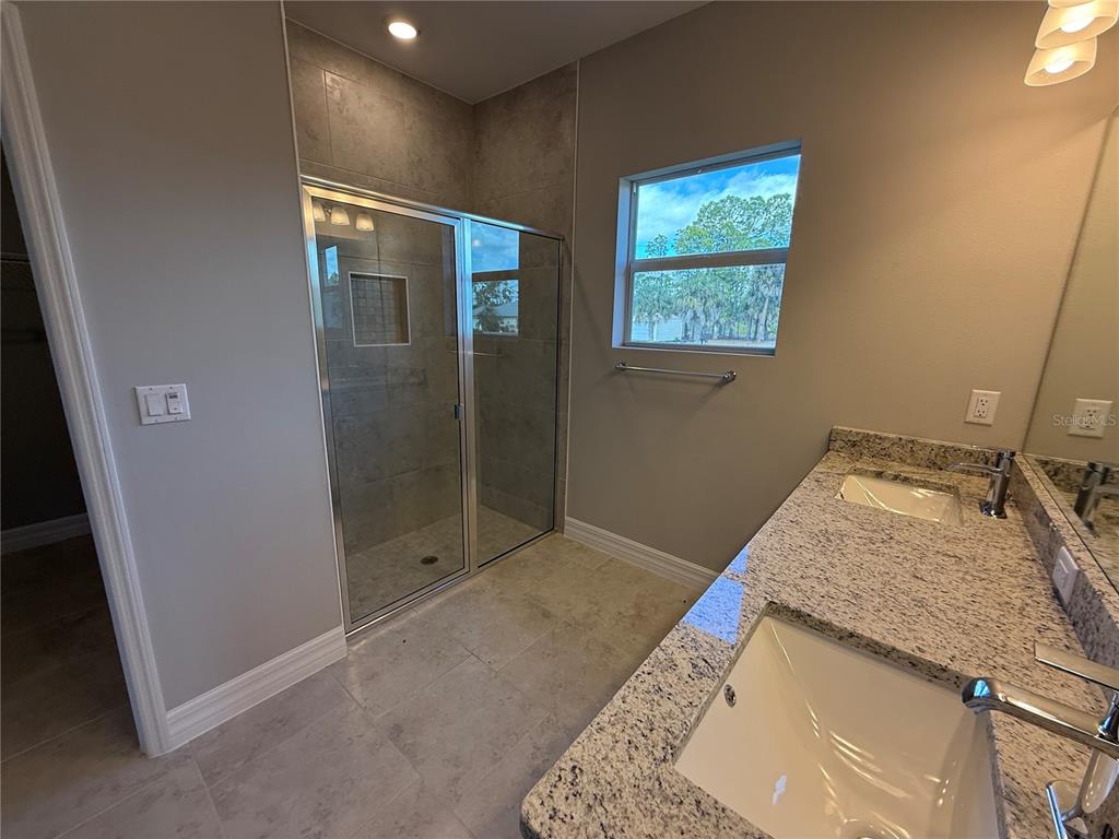 2268 Brewster Road North Port, FL 34288 - Photo 15 of 33 a bathroom with a granite countertop sink a mirror and shower