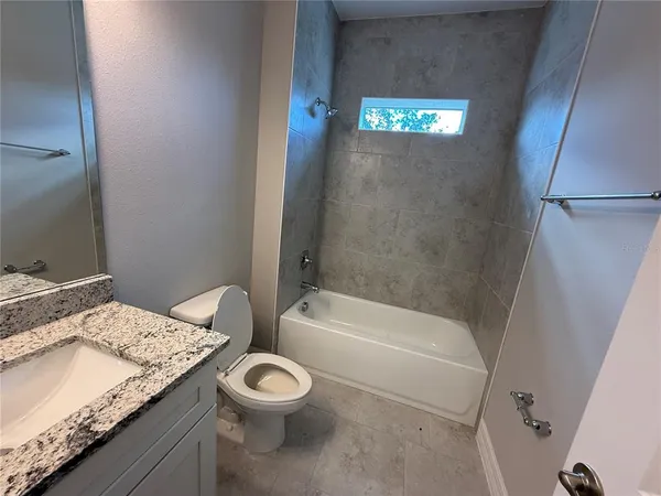 a bathroom with a granite countertop sink a toilet and bathtub