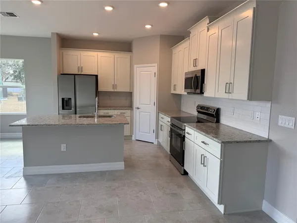 a large kitchen with stainless steel appliances granite countertop a large counter top a stove a sink and a refrigerator