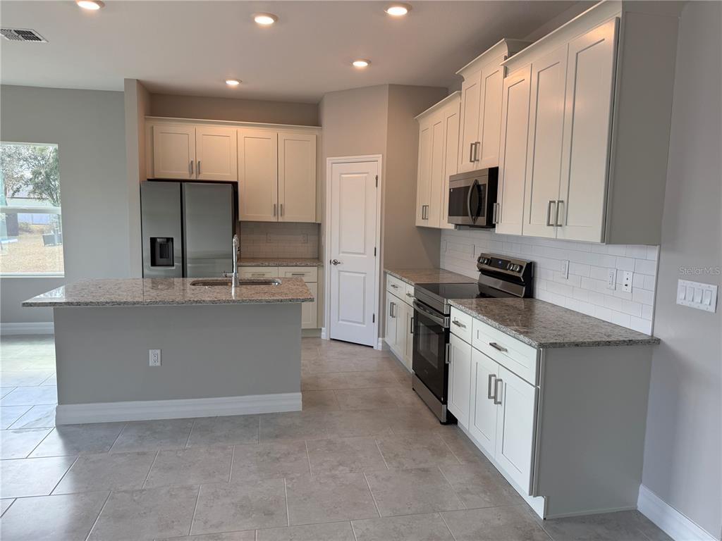 2268 Brewster Road North Port, FL 34288 - Photo 5 of 33 a large kitchen with stainless steel appliances granite countertop a large counter top a stove a sink and a refrigerator