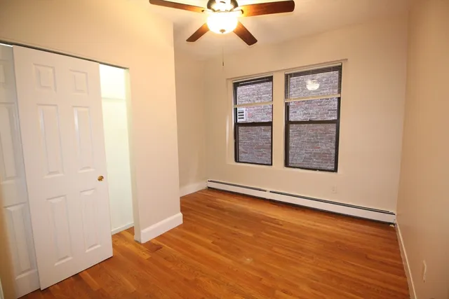 an empty room with wooden floor closet and windows