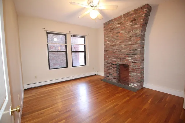 an empty room with wooden floor chandelier fan and windows