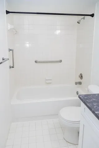 a bathroom with a granite countertop bathtub shower and toilet