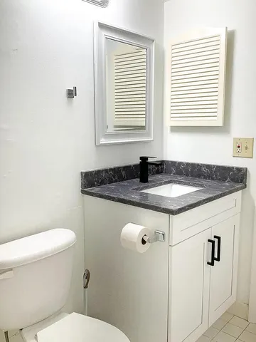 a bathroom with a granite countertop sink and a toilet