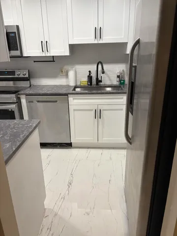 a kitchen with stainless steel appliances granite countertop a sink a stove a refrigerator a washer dryer and cabinets