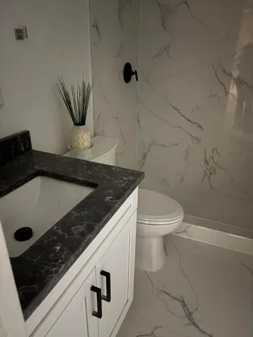 a bathroom with a granite countertop sink a toilet and a tub