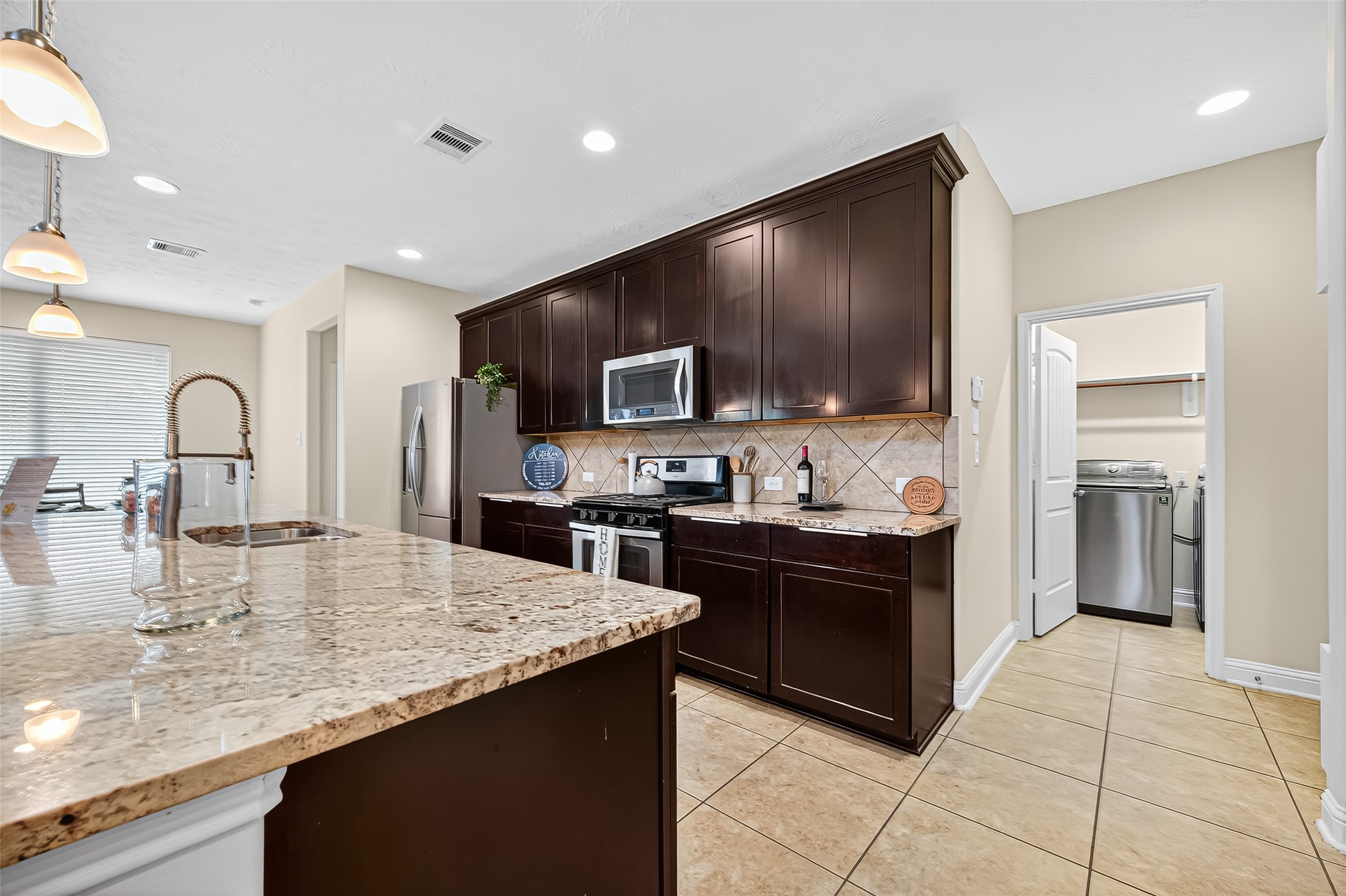 8107 Lockridge Terrace Lane Cypress, TX 77433 - Photo 14 of 50 This gourmet kitchen is a chef’s dream, featuring rich espresso cabinetry, gleaming granite countertops, and stainless steel appliances. The oversized island invites gathering and conversation, while the adjacent walk-in pantry offers ample storage. With elegant tile flooring and seamless flow into the living and dining areas, it’s the heart of the home where meals—and memories—are made.