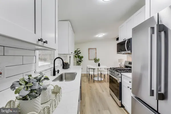 a kitchen with stainless steel appliances granite countertop a stove top oven a sink dishwasher and a refrigerator with wooden floor