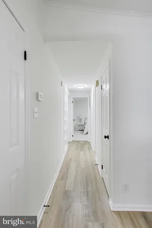 a view of a hallway with wooden floor and a bathroom