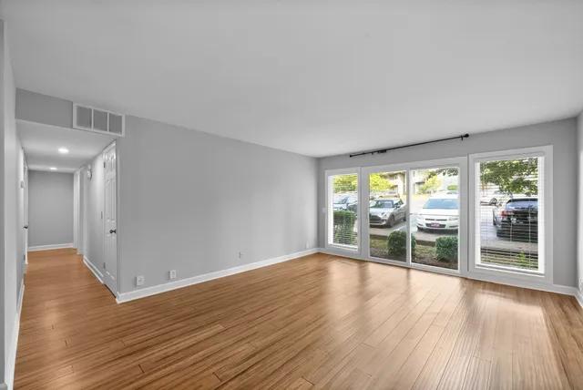 a view of a room with wooden floor chandeliers and kitchen view