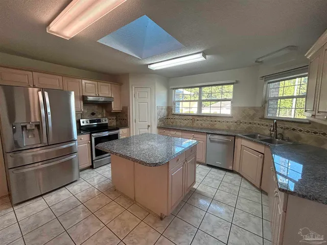 a kitchen with stainless steel appliances granite countertop a stove a sink dishwasher a refrigerator and a microwave