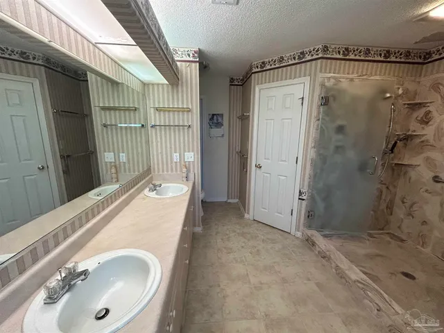 a bathroom with a granite countertop sink a mirror and shower