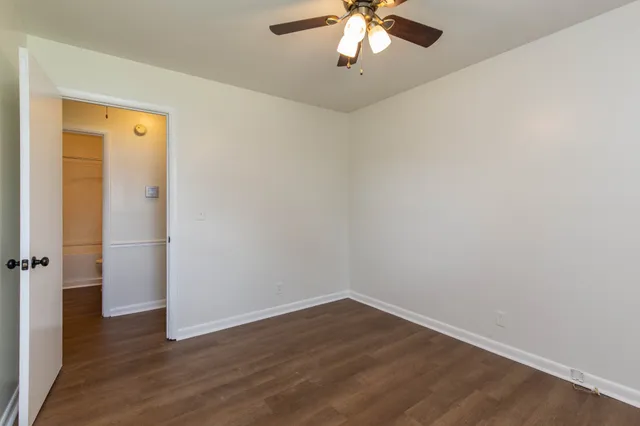 an empty room with wooden floor and chandelier fan