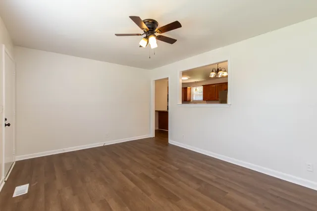 an empty room with wooden floor and ceiling fan