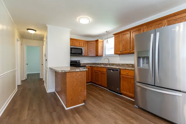 a kitchen with stainless steel appliances granite countertop a refrigerator a sink dishwasher a stove with wooden floor and cabinets