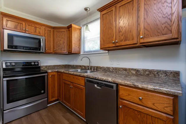 a kitchen with stainless steel appliances granite countertop a stove microwave and sink with wooden cabinets