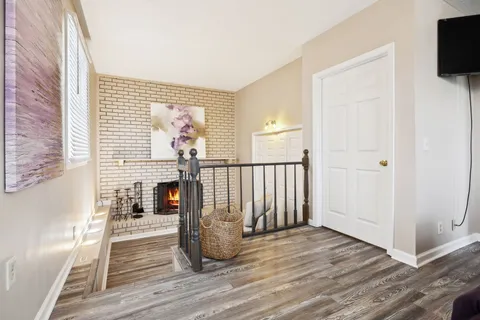 a view of a livingroom with wooden floor and a fireplace