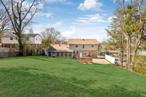 a view of a house with a big yard and large trees