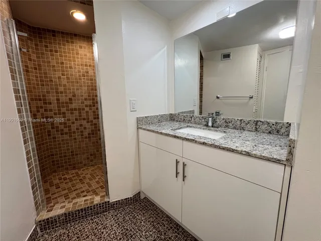 a bathroom with a granite countertop sink a toilet and shower