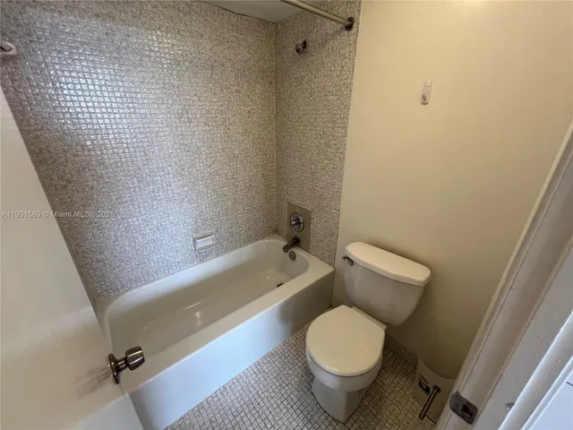 a bathroom with a granite countertop toilet and a bathtub