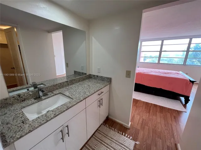 a bathroom with a granite countertop sink and a mirror