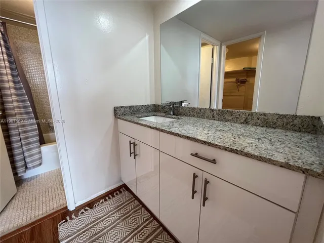 a bathroom with a granite countertop sink and a mirror