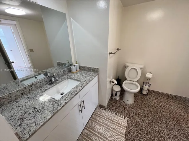 a bathroom with a granite countertop toilet and a sink