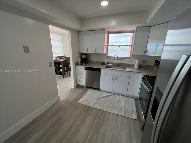 a kitchen with granite countertop a sink a stove cabinets and wooden floor