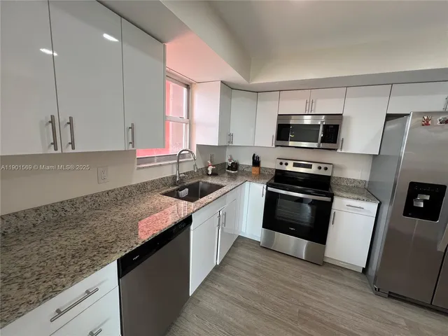 a kitchen with stainless steel appliances granite countertop a sink a stove a refrigerator a sink a microwave and wooden cabinets