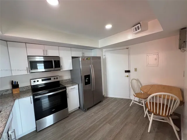 a kitchen with stainless steel appliances wooden floor and a refrigerator