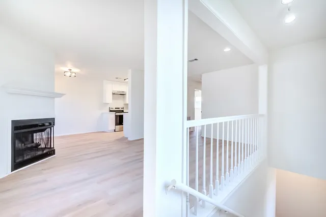 a view of a hallway with wooden floor and a kitchen